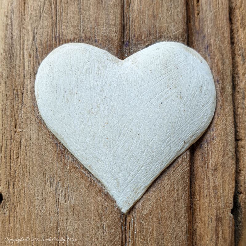 A beautiful clay heart embedded onto a well-worn piece of wood