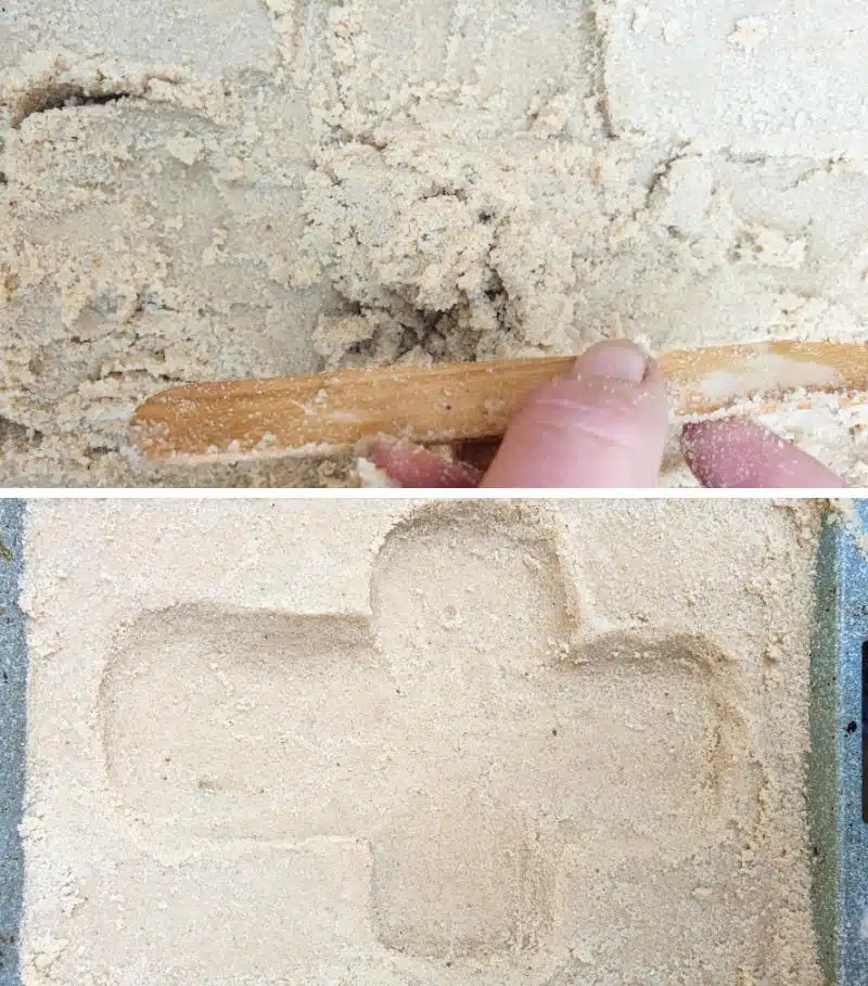 Use your hands and and ice cream stick to carve a cross shape into the wet sand.