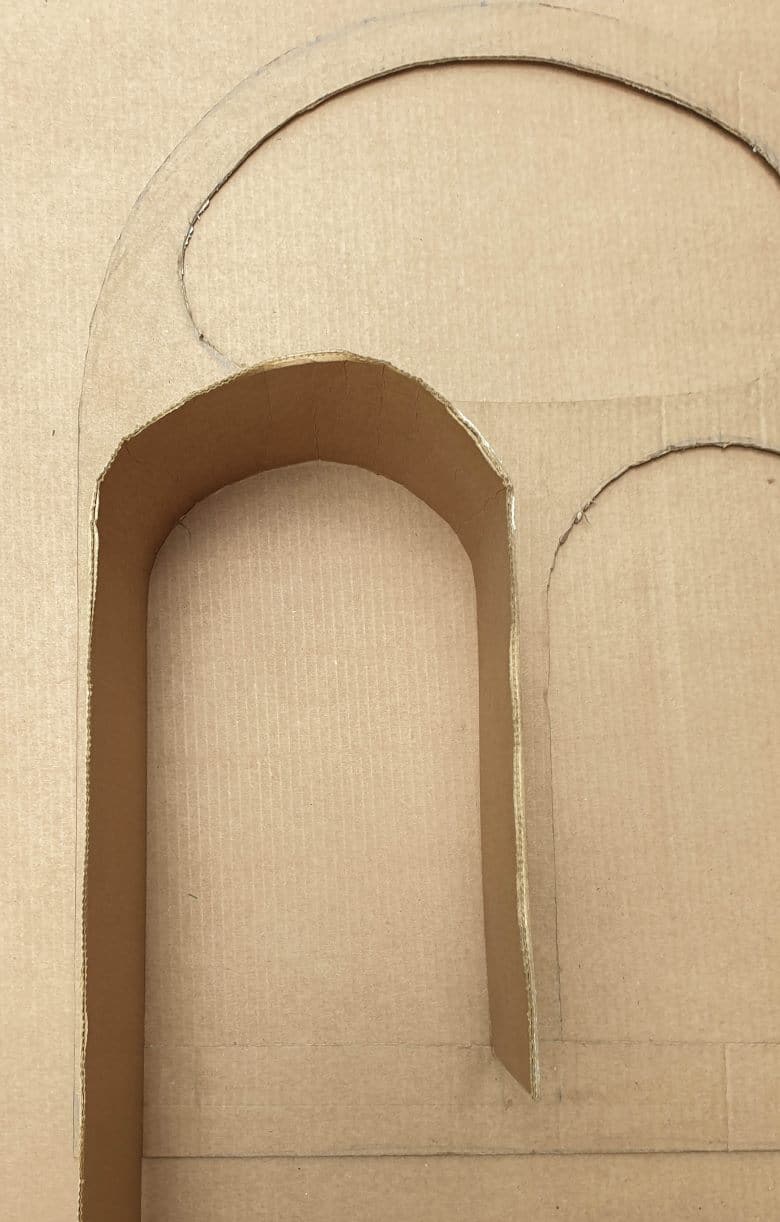 Bend the cardboard strips around the cut out pieces to create a wall