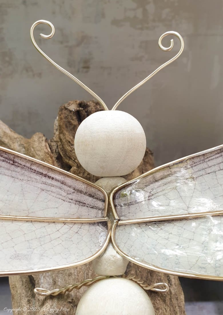 This easy tutorial will who you how to create a large wooden bead dragonfly that is sure to be a conversation starter in any room. You can experiment with different colors, shapes, and sizes to create a one-of-a-kind dragonfly that reflects your personal style and creativity. #ACraftyMix