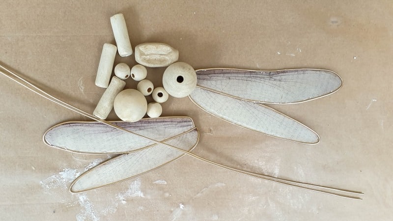 A collection of beads and resin book page wings that will be used to make the dragonfly