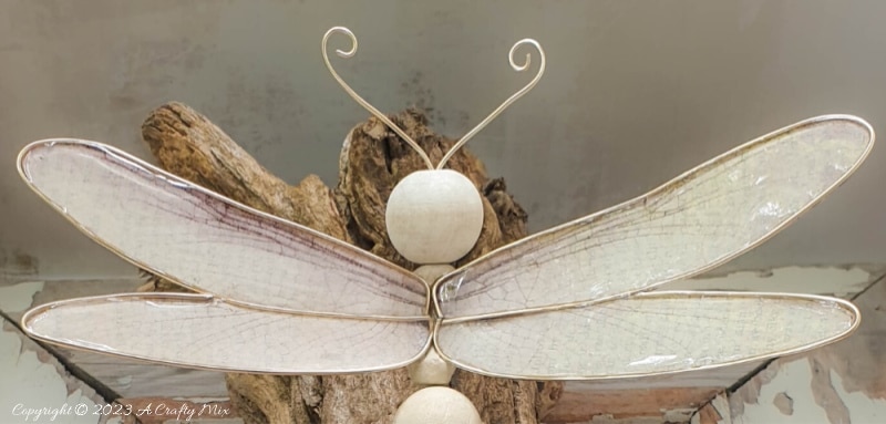 This easy tutorial will who you how to create a large wooden bead dragonfly that is sure to be a conversation starter in any room. You can experiment with different colors, shapes, and sizes to create a one-of-a-kind dragonfly that reflects your personal style and creativity. #ACraftyMix