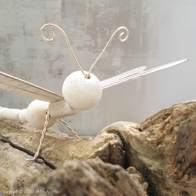 This easy tutorial will who you how to create a large wooden bead dragonfly that is sure to be a conversation starter in any room. You can experiment with different colors, shapes, and sizes to create a one-of-a-kind dragonfly that reflects your personal style and creativity. #ACraftyMix