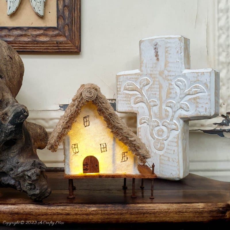 This paper house with a miniature thatch roof is made entirely from scraps and recycled materials, giving it a creative, whimsical feel. The lights add a little magic, and we all need more of that in our lives. In this step-by-step tutorial, we’ll show you how you can make your own and share an easy way to thatch a small roof. #ACraftyMix