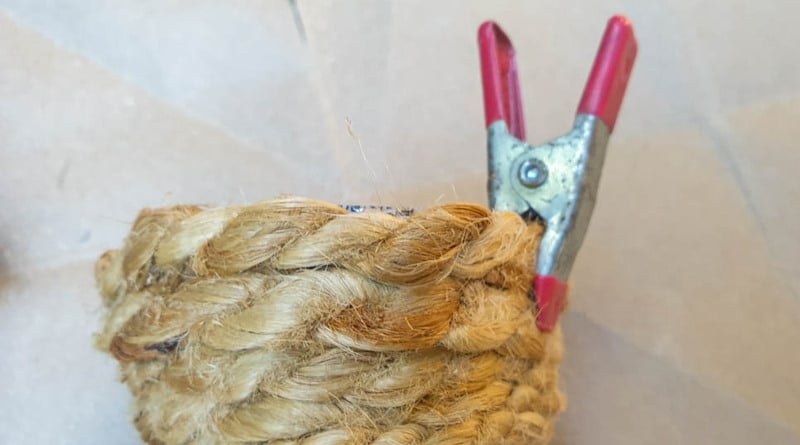 Use a small spring clip or peg to hold the rope in place while the glue dries