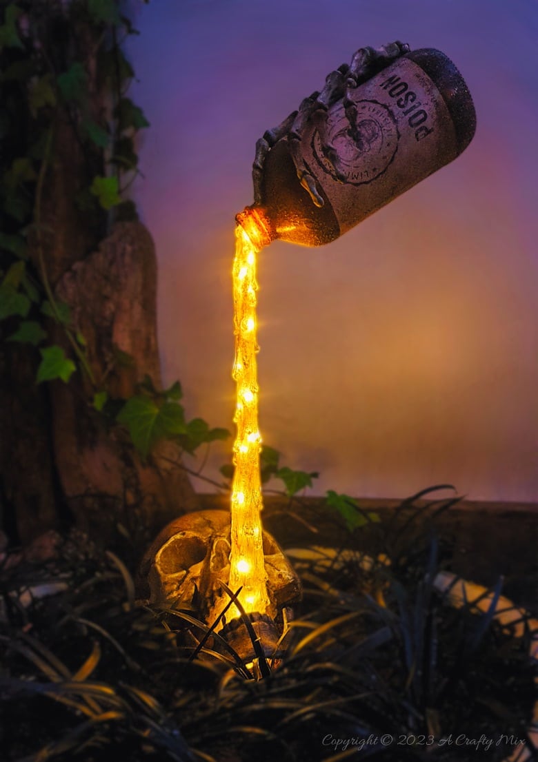 Unleash your inner sorcerer with this DIY Skull and Floating Bottle Planter tutorial! We&rsquo;ll show you how to get the bottle to defy gravity and create a dripping poison effect that casts an otherworldly glow over the scene at night. The tutorial includes a free poison label printable and loads of pictures to guide you through the process. No special tools needed. #ACraftyMix