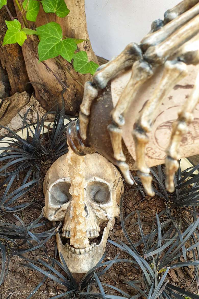 Unleash your inner sorcerer with this DIY Skull and Floating Bottle Planter tutorial! We’ll show you how to get the bottle to defy gravity and create a dripping poison effect that casts an otherworldly glow over the scene at night. The tutorial includes a free poison label printable and loads of pictures to guide you through the process. No special tools needed. #ACraftyMix