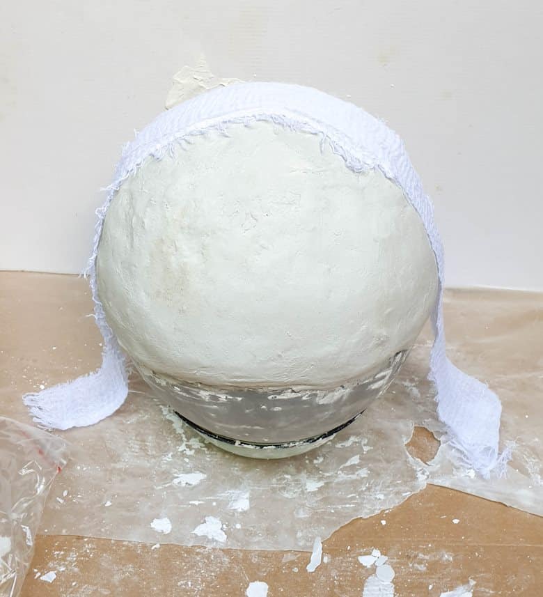 Lay the strip of fabric over the balloon with casting stone