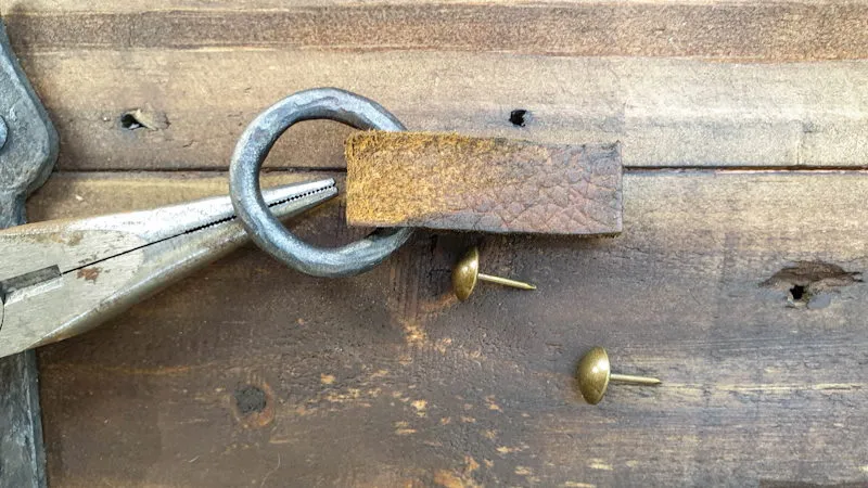 Add the leather strip to the clay rings and use thumb tacks to attached the door pull to the doors