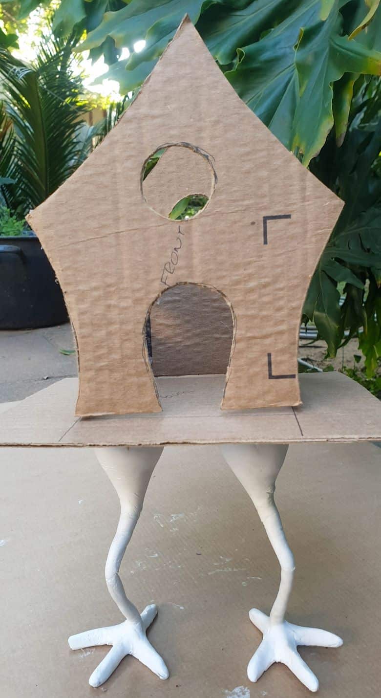 Work-in-progress and balancing Baba Yaga's hut on a cardboard platform resting on wiry chicken legs