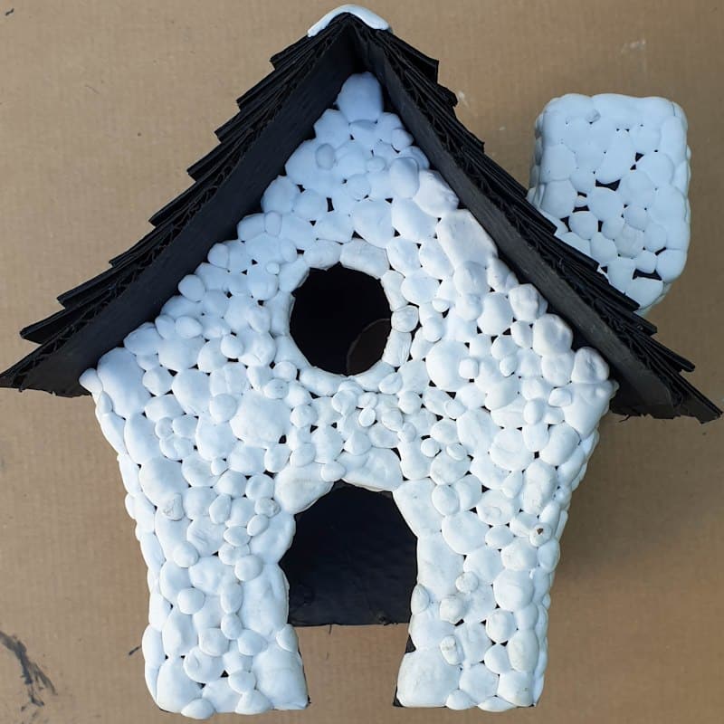 A cardboard hut clad in foam clay stones