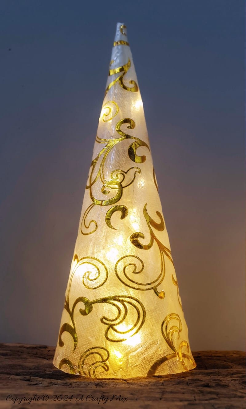 Get ready to add a little sophistication to your decor with these elegant and easy to make tabletop trees that will brighten up any room in your home. Made from paper napkins and filled with fairy lights, these Christmas decorations are perfect for small spaces and look beautiful on a table, mantle or bookshelf. Go glam with hints of gold or use napkins that match your table d&eacute;cor.