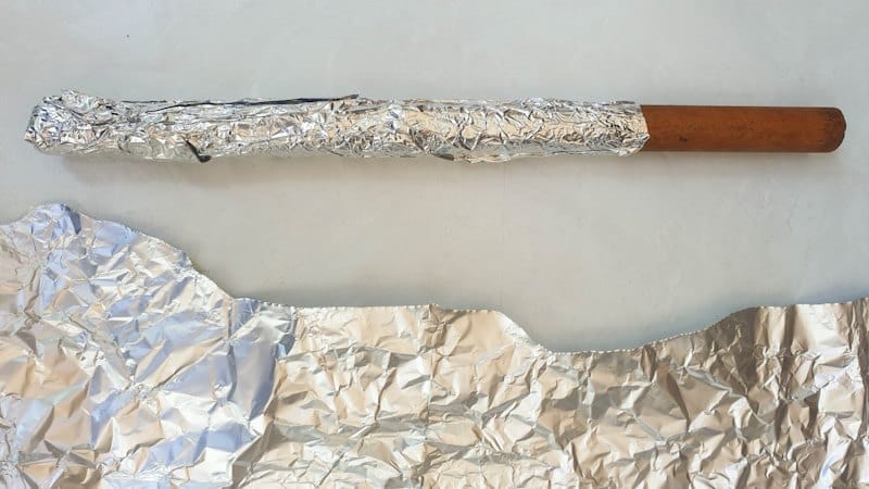 Wraps tin foil around a dowel or branch