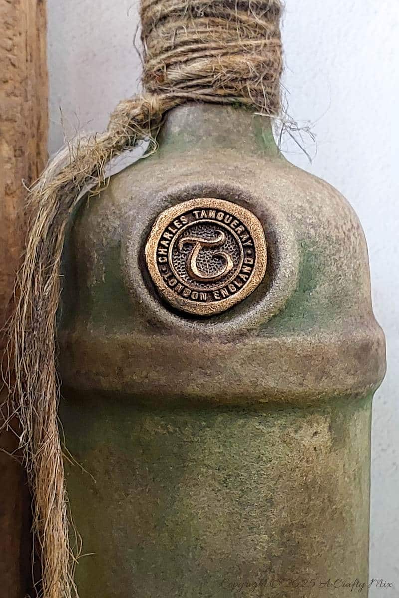 Upcycle ordinary bottles into old world treasures with this easy DIY. This beginner-friendly tutorial teaches you how to create an authentic antique clay finish using simple powdered food coloring and texture paste. Perfect for rustic or old-world d&eacute;cor.