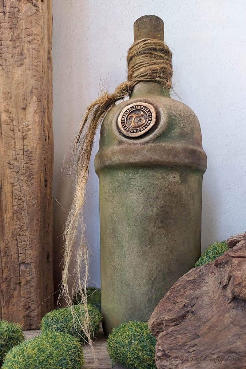 Upcycle ordinary bottles into old world treasures with this easy DIY. This beginner-friendly tutorial teaches you how to create an authentic antique clay finish using simple powdered food coloring and texture paste. Perfect for rustic or old-world d&eacute;cor.