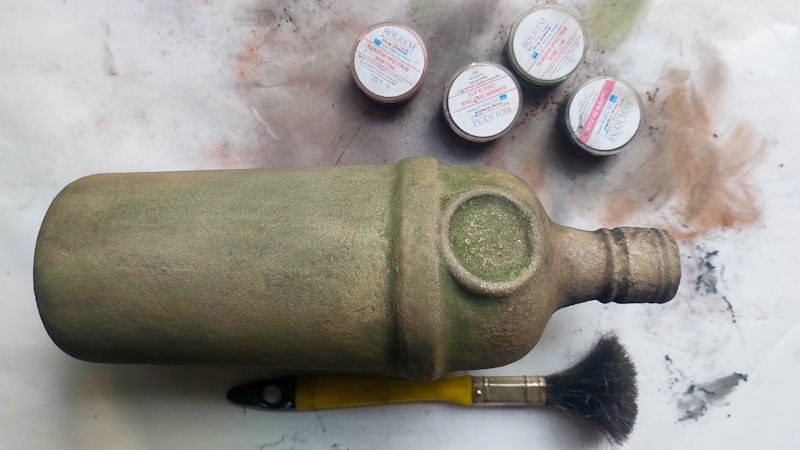 Upcycle ordinary bottles into old world treasures with this easy DIY. This beginner-friendly tutorial teaches you how to create an authentic antique clay finish using simple powdered food coloring and texture paste. Perfect for rustic or old-world d&eacute;cor.