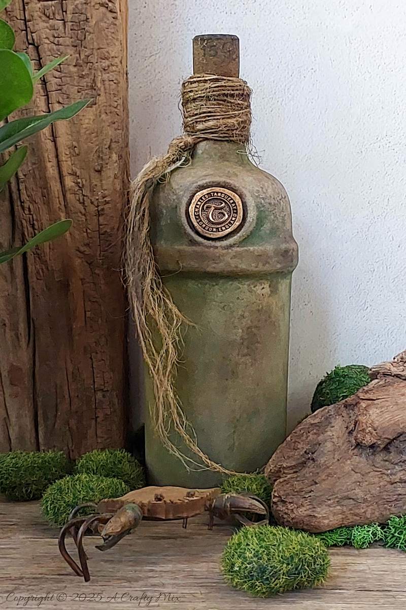 Upcycle ordinary bottles into old world treasures with this easy DIY. This beginner-friendly tutorial teaches you how to create an authentic antique clay finish using simple powdered food coloring and texture paste. Perfect for rustic or old-world d&eacute;cor.