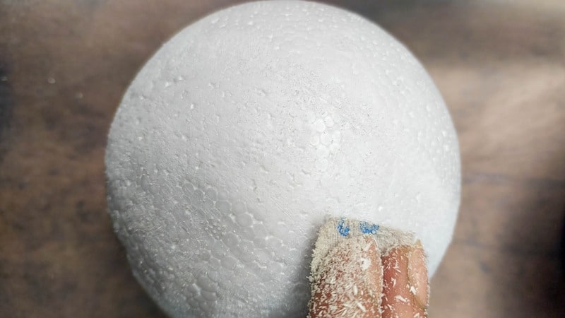 Sand the polystyrene (styrofoam) ball to smooth it out