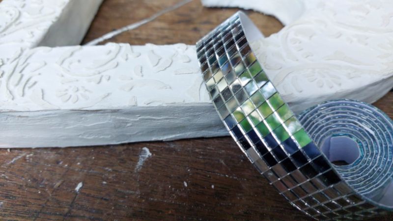 Glue mirror tiles along the outer edge of the cardboard hearts