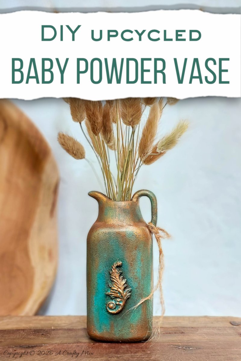 Vertical image of a faux verdigris patina vase made from an upcycled baby powder bottle, with dried grasses arranged in the jug‑style vase and text overlay that reads &ldquo;DIY upcycled baby powder vase.