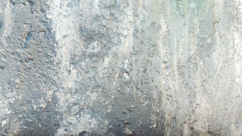 A close up of a gritty, grey, textured layer of paint