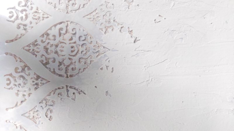 A Damask stencil with stencil texture paste applied on one corner