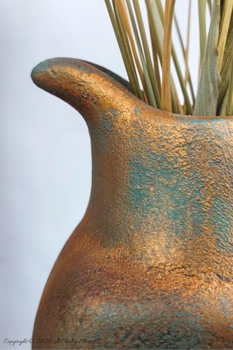 Close up of the a faux verdigris patina on a vase made from an upcycled baby powder bottle.