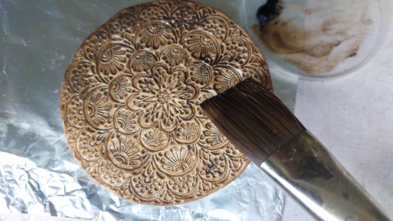 Applying the oil paint to the rustic clay medallion