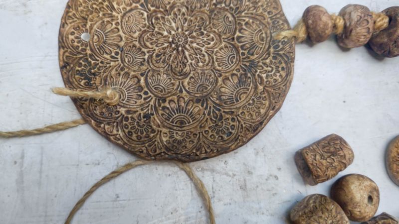 A top down image of the clay medallion and jute twine threaded through the holes