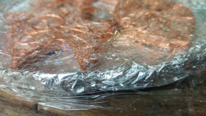 Copper fish lie on a tin foil base covered in cling wrap (Saran wrap)