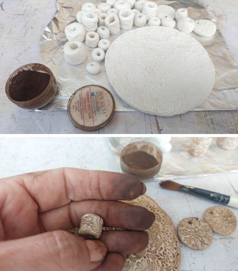 Collage showing the process of colouring a DIY clay medallion and beads: the top image has white embossed clay pieces laid out on foil beside an open pot of brown powdered pigment, and the bottom image shows stained fingers holding a newly coloured textured clay bead above the partially shaded medallion, pigment pot, and brush.