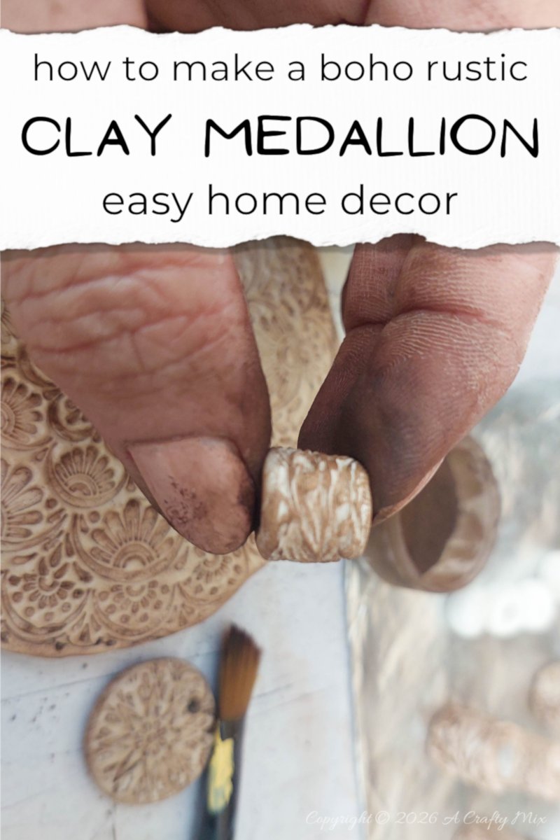 Close‑up Pinterest pin showing paint‑stained fingers holding a small textured clay bead in front of an embossed clay medallion and tools, with the text &ldquo;how to make a boho rustic clay medallion &ndash; easy home decor&rdquo; above.