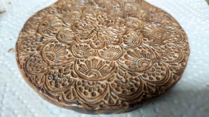 A close up of the rustic, boho clay medallion