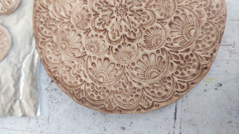 A close up shot of the clay medallion after it's been dusted with food coloring
