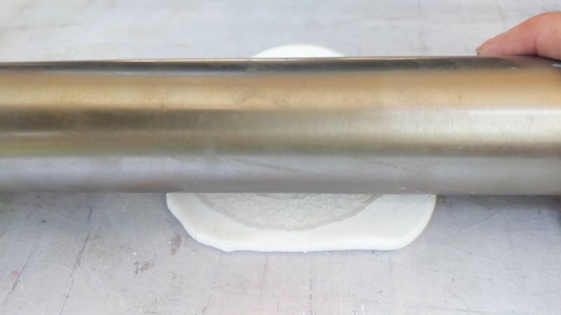 A close up shot of a rolling pin and, silicone mold and clay