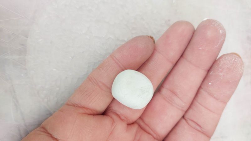 A hand holding a small ball of clay