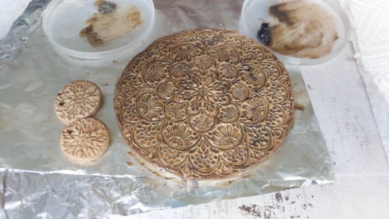 A close up view of the rustic, boho clay medallion.