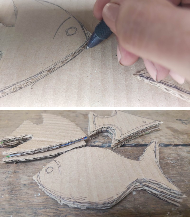 A hand tracing around simple cardboard fish shapes