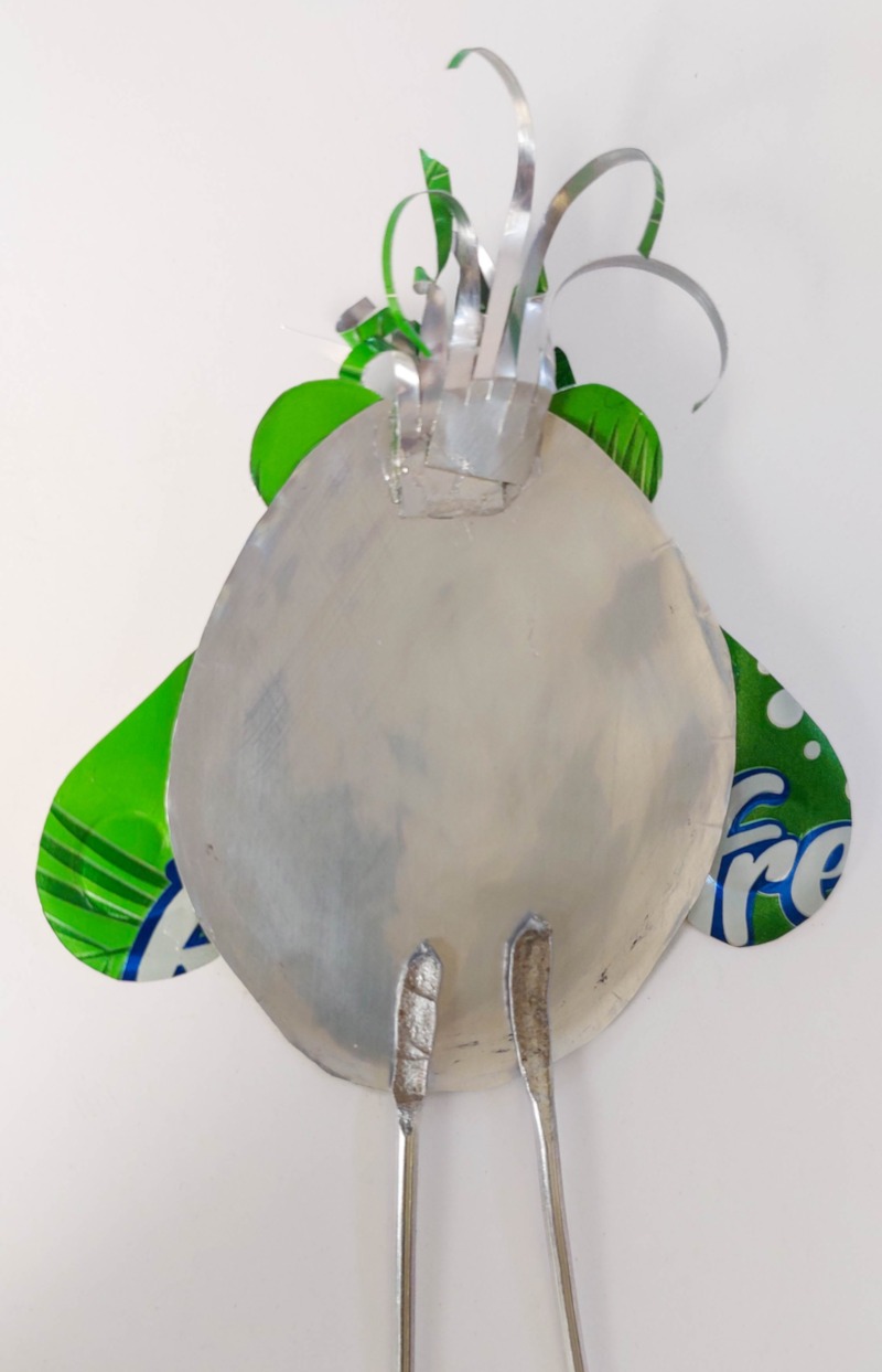 Back view of a green soda can bird showing how the curled crest and flattened wire legs are glued onto the aluminium body.