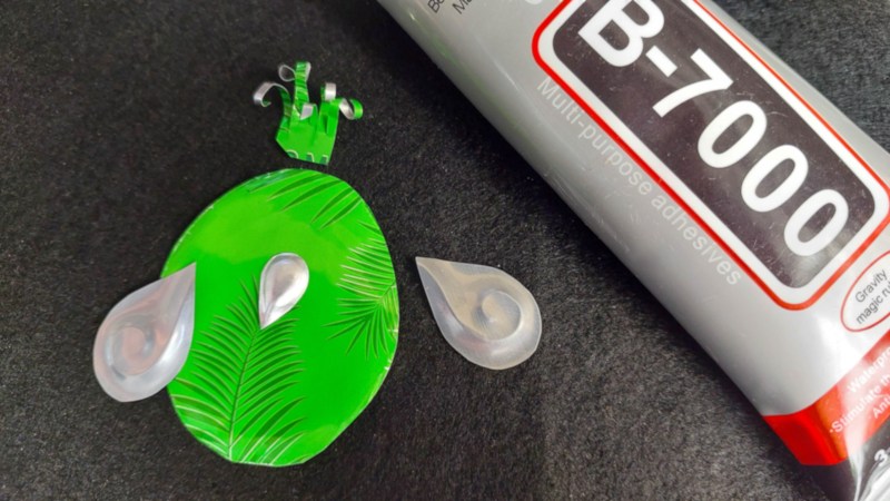 A tube of glue lies next to aluminium shapes on a black felt mat.
