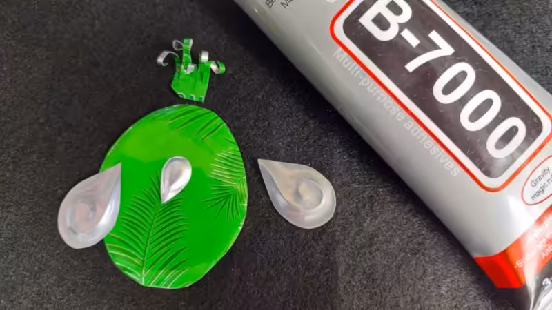 A tube of glue lies next to aluminium shapes on a black felt mat.