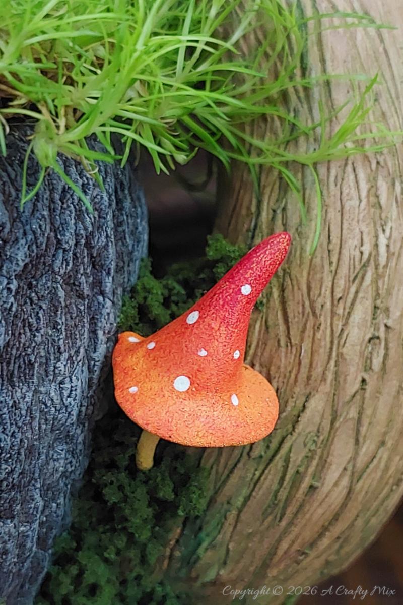 A small mushroom or toadstoool nestles at the base of a larger mushroom attached to a teacup.