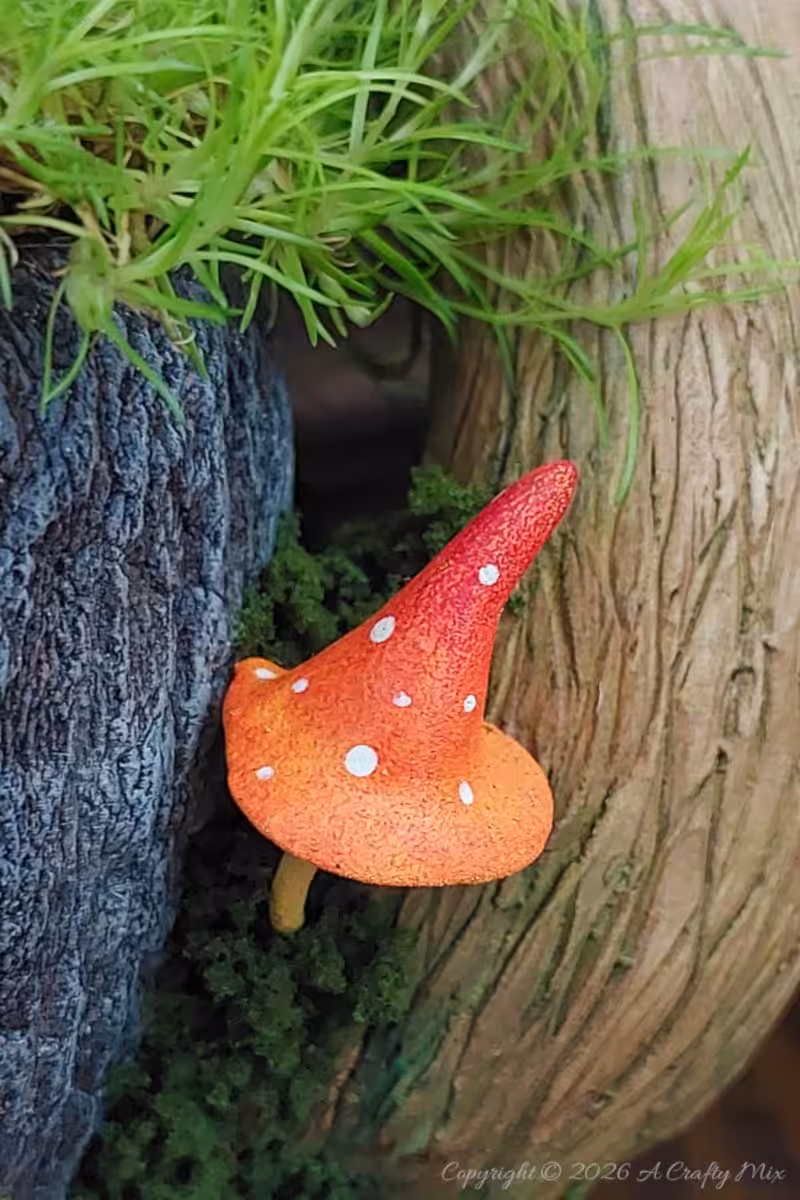 A small mushroom or toadstoool nestles at the base of a larger mushroom attached to a teacup.