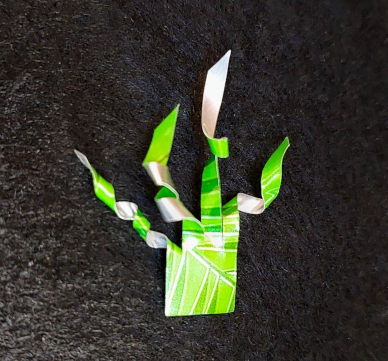 Close up of a green aluminium can that's been cut to resemble a crest.