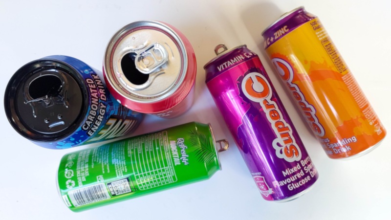 Five brightly coloured soda cans on a white background