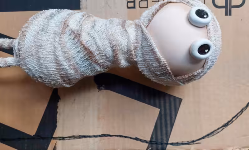 Make a tiny sarcophagus from scrap cardboard for your DIY Halloween mummy. This easy upcycling step shows how simple cardboard strips and a curved base become the shape for a weathered faux-stone tomb. Save it for your next not-too-spooky Halloween craft.