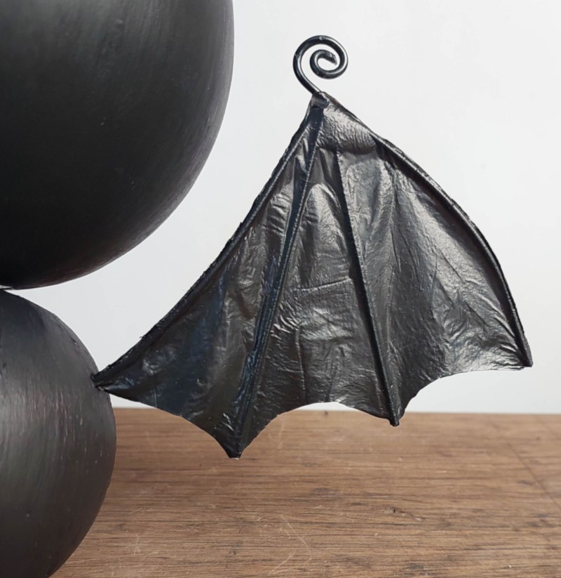Close up view of a cute black hanging bat with recycled plastic bag wings before adding large sparkling eyes.