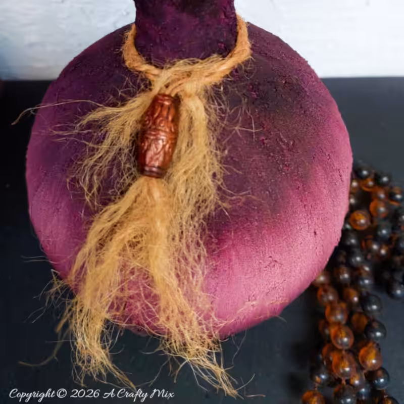 Close-up of the jute rope and carved bead tied around the neck of an upcycled Plum Noir DIY vase, highlighting the texture and color blend.