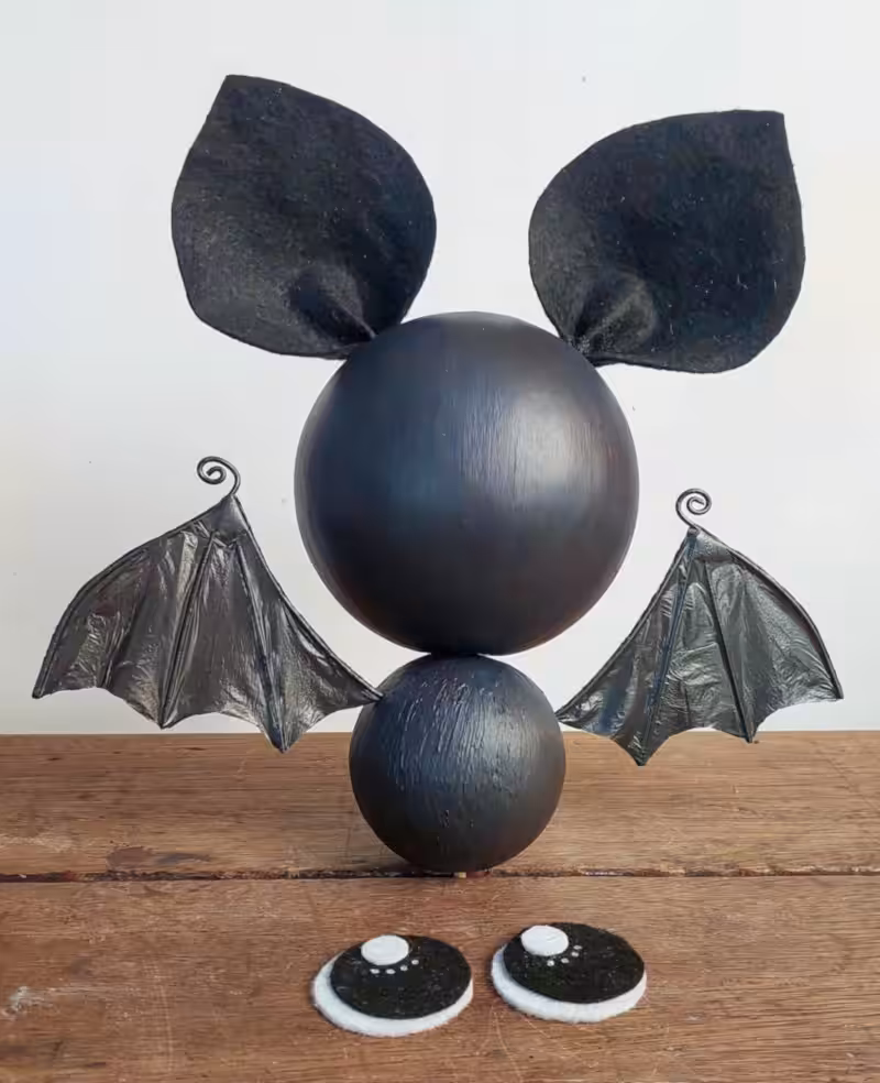Front view of a cute black hanging bat with recycled plastic bag wings before adding large sparkling eyes.