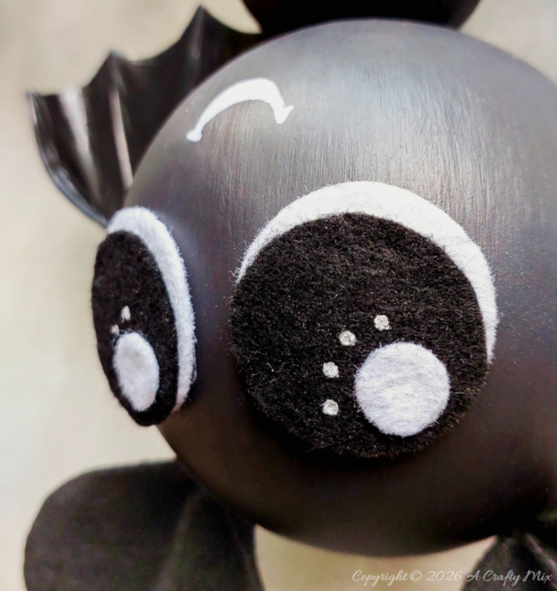Close-up of the DIY bat&rsquo;s large black felt eyes with white outlines, white catchlights, and small sparkle details.
